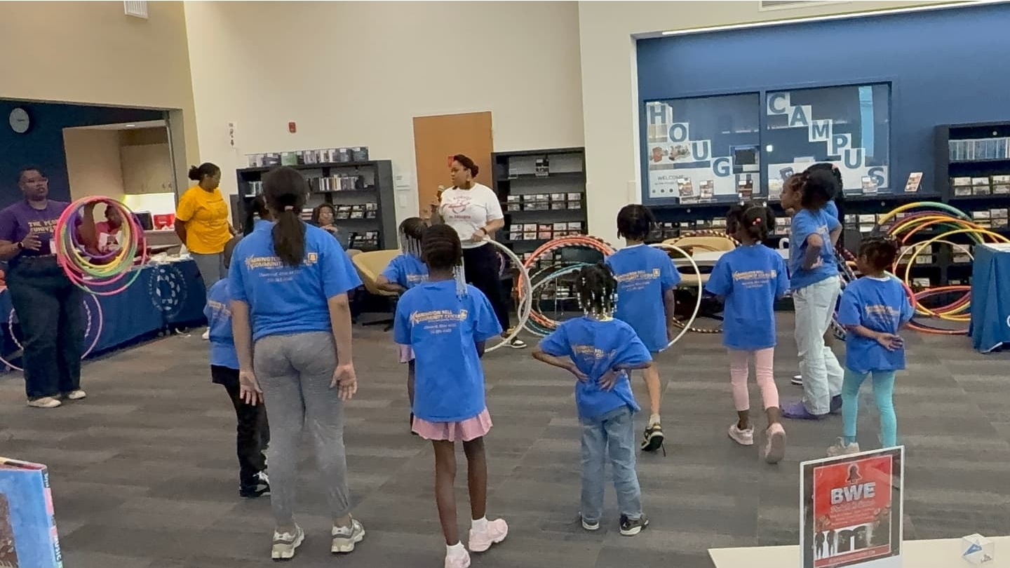 An instructor leading children and adults during a Curves N Hoops class at a library